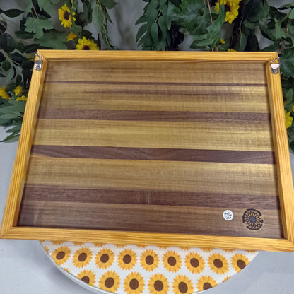 Wooden wall art with a sunflower-patterned cloth underneath, surrounded by greenery.