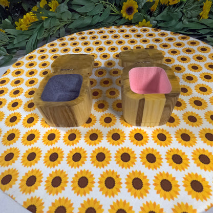 Two wooden jewelry boxes with colorful cushions on a sunflower-patterned tablecloth.