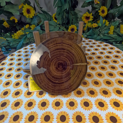 Wooden coasters on a tablecloth with sunflower pattern, surrounded by flowers and greenery
