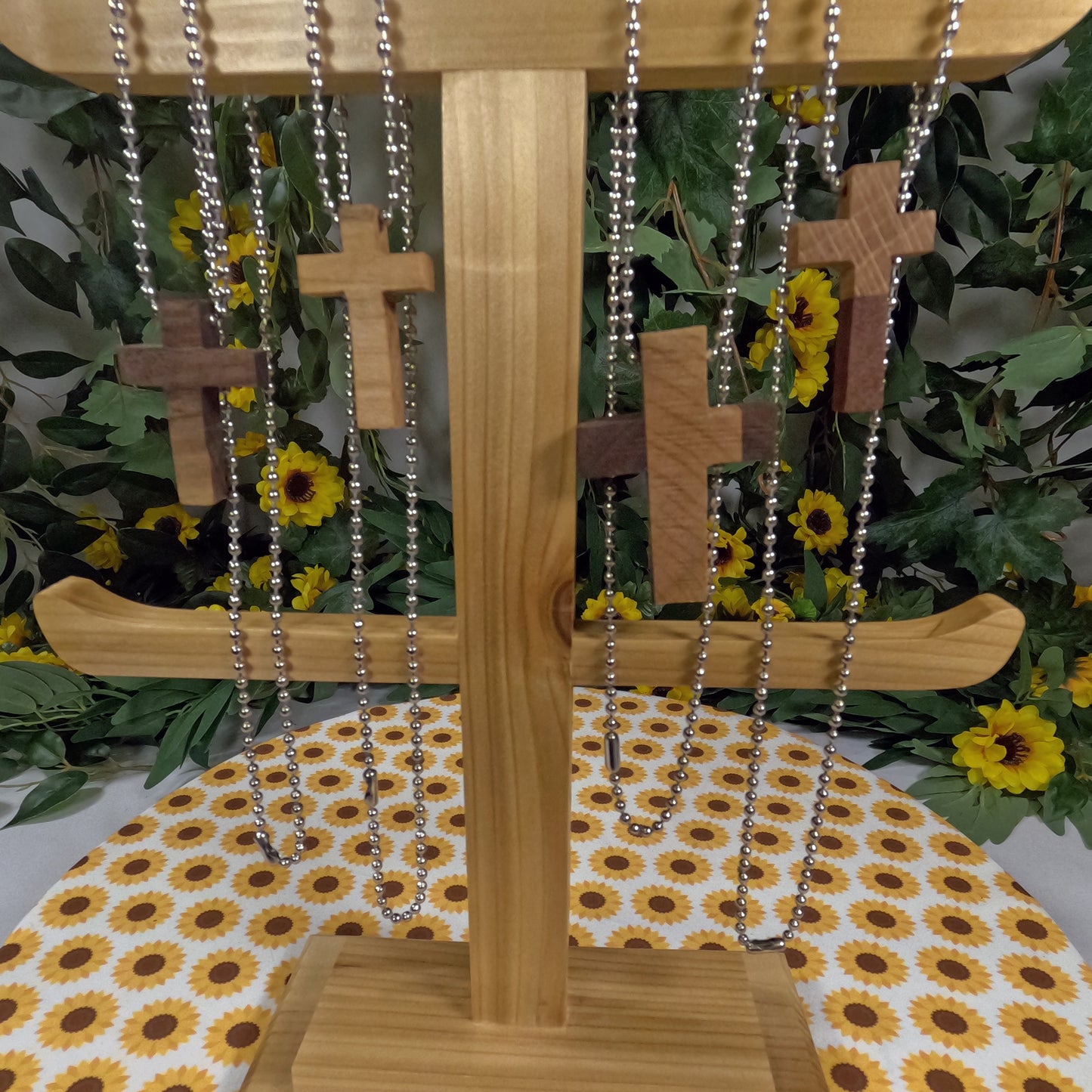 Wooden stand with cross necklaces on a floral tablecloth