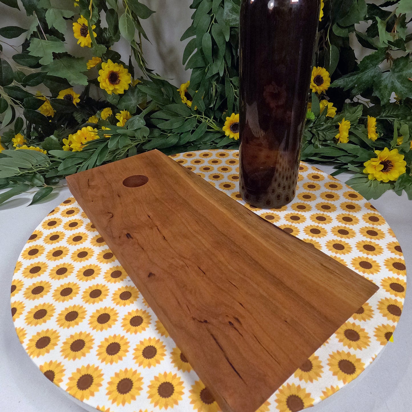 Wooden wine bottle holder on a sunflower-patterned placemat with wine bottle in the background.