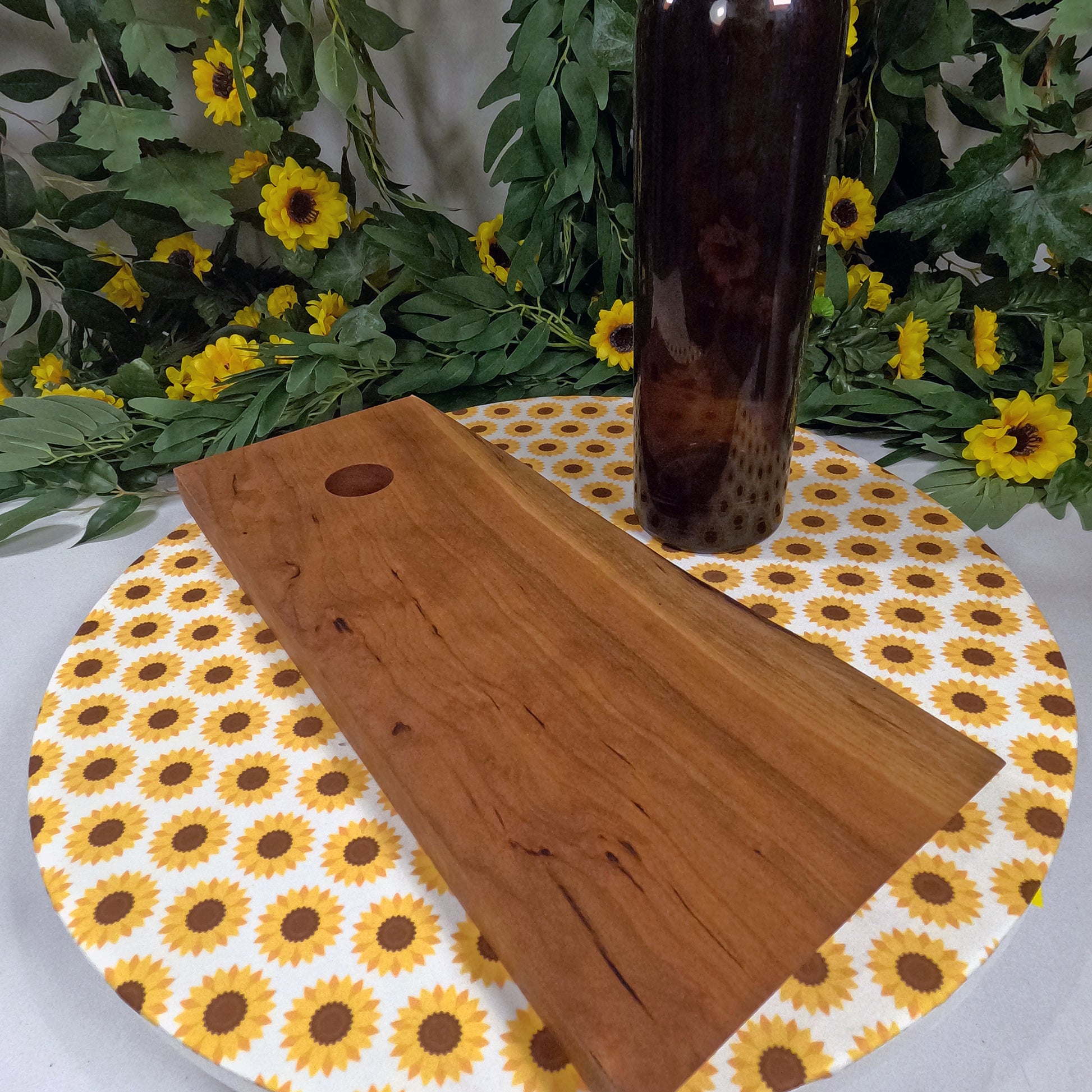 Wooden wine bottle holder on a sunflower-patterned placemat with wine bottle in the background.