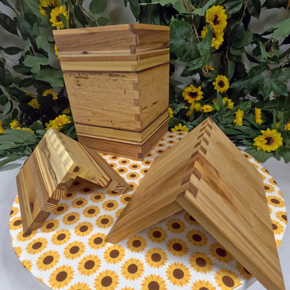 Wooden book stands on a tablecloth with sunflower pattern, surrounded by greenery and flowers.