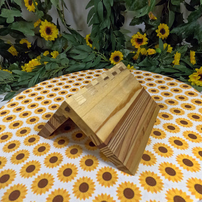 Wooden book stands on a tablecloth with sunflower pattern, surrounded by greenery and flowers.