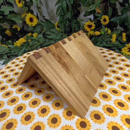Wooden book stand on a tablecloth with sunflower pattern, surrounded by greenery and flowers.