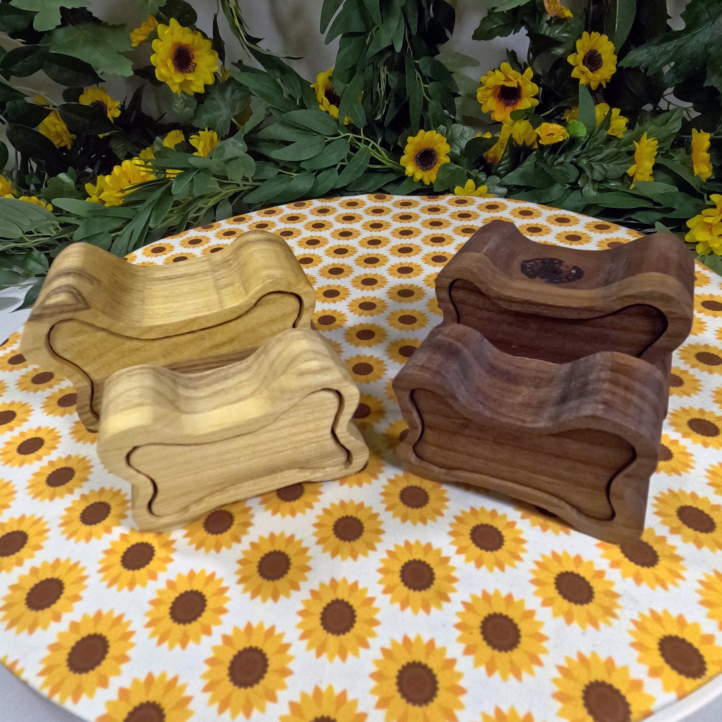 Three wooden dog bone boxes on a tablecloth with sunflower pattern