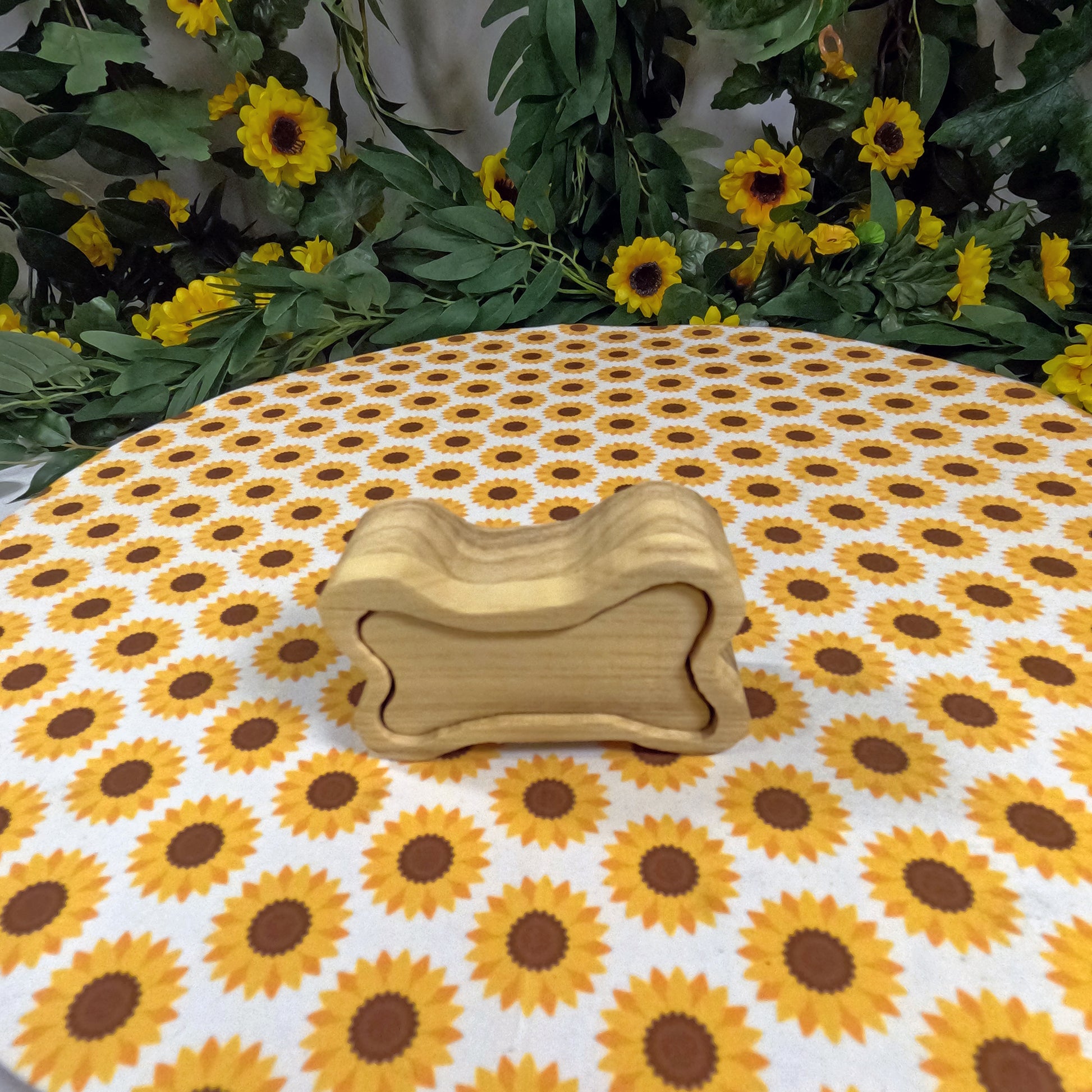 Wooden dog bone-shaped box on a tablecloth with sunflower pattern