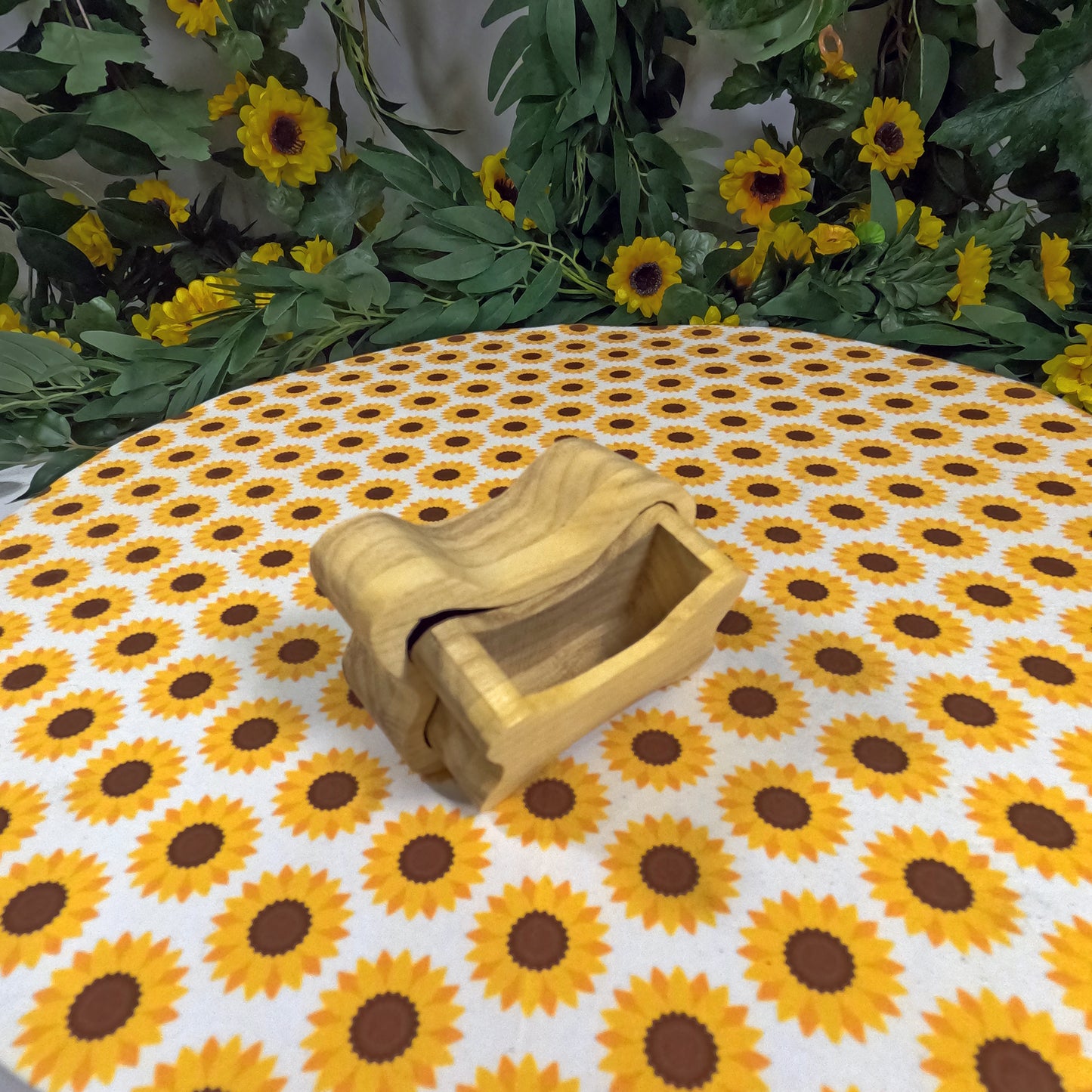 Wooden dog bone-shaped box on a tablecloth with sunflower pattern