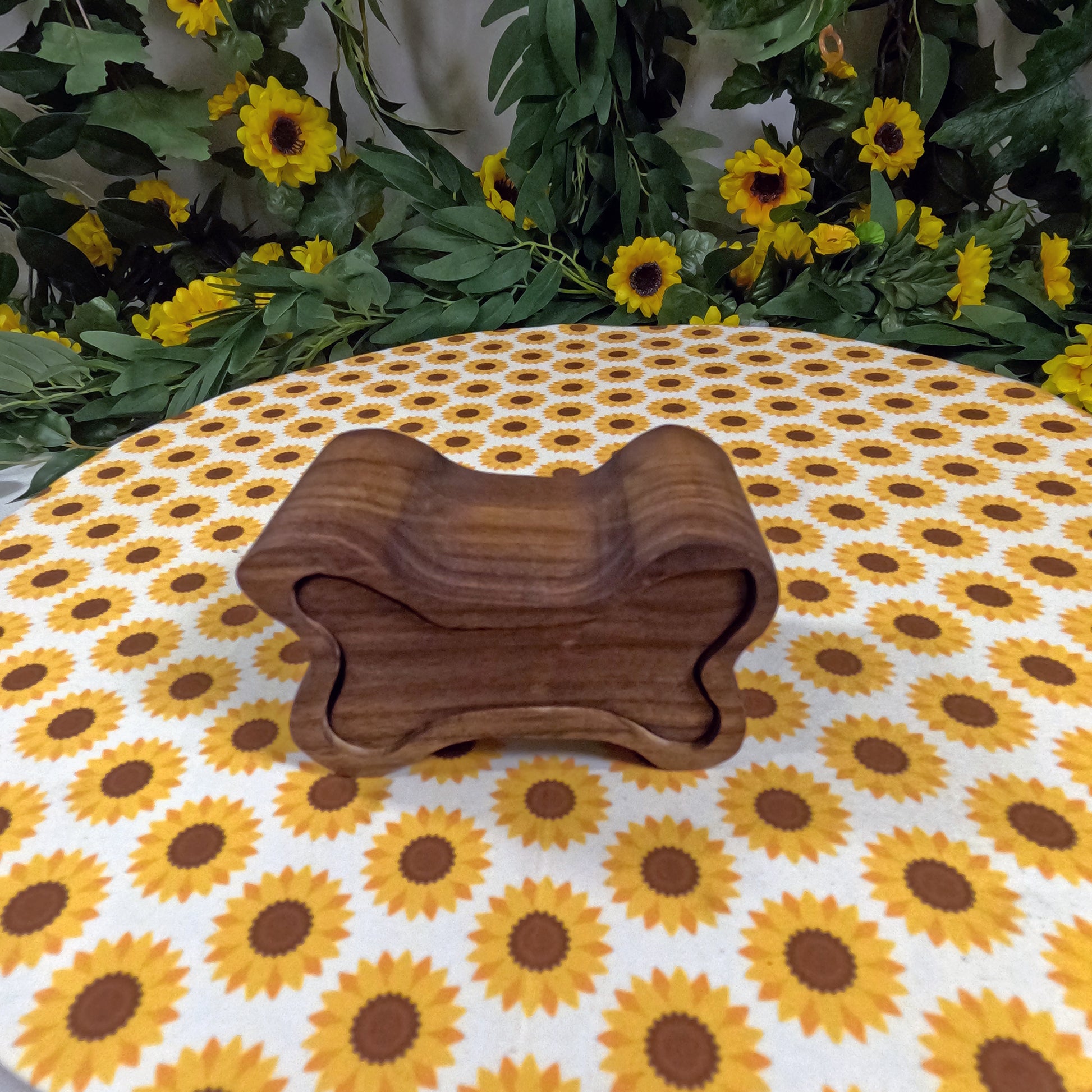 Wooden dog bone-shaped box on a tablecloth with sunflower pattern