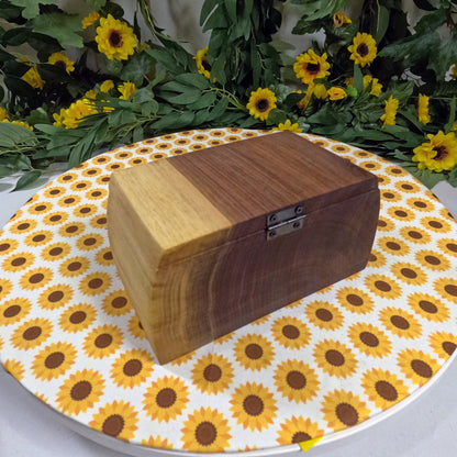 Wooden box on a tablecloth with sunflower pattern, surrounded by greenery and yellow flowers.