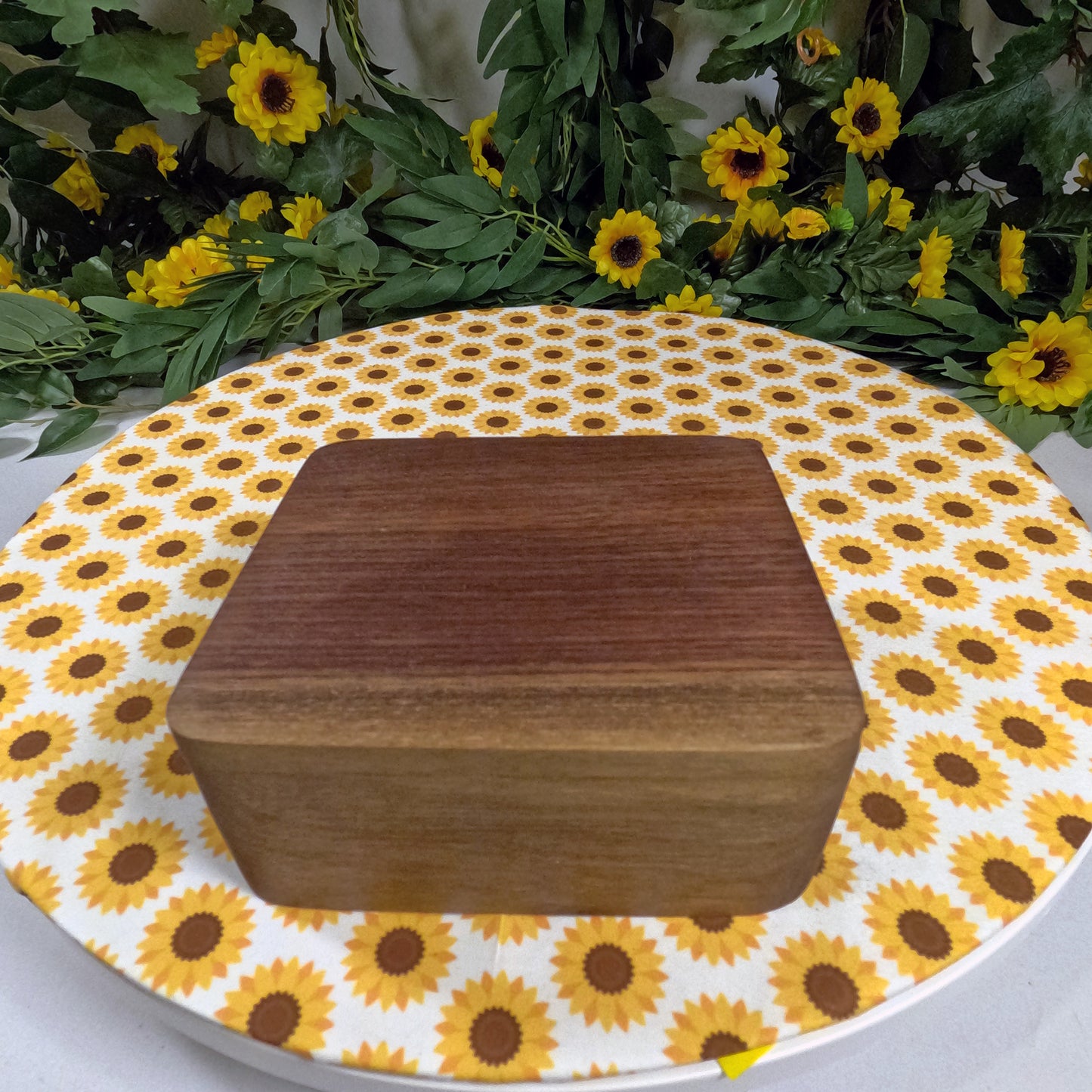 Wooden box on a sunflower-patterned tablecloth with flowers in the background