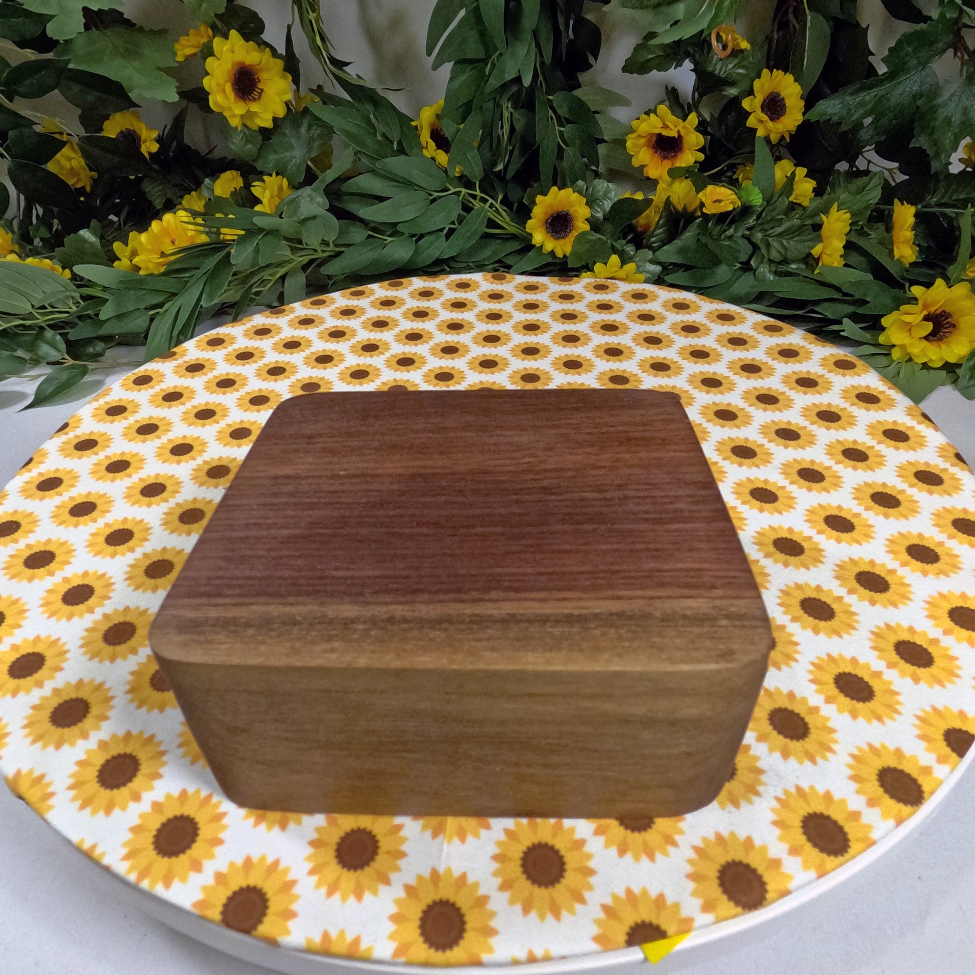 Wooden box on a sunflower-patterned tablecloth with flowers in the background