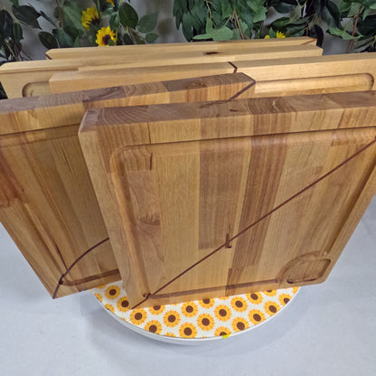 Set of wooden cutting boards on a white surface with a floral patterned plate underneath.