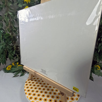 White canvas on an easel with a floral patterned tablecloth and greenery in the background