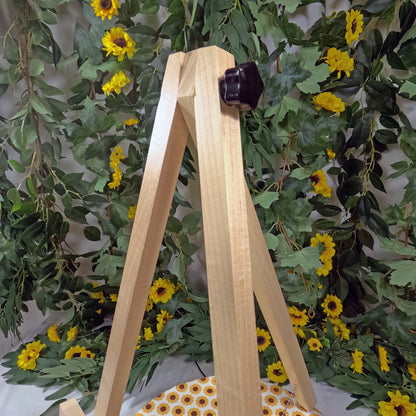 Wooden tongs with a dark handle against a backdrop of green leaves and yellow flowers