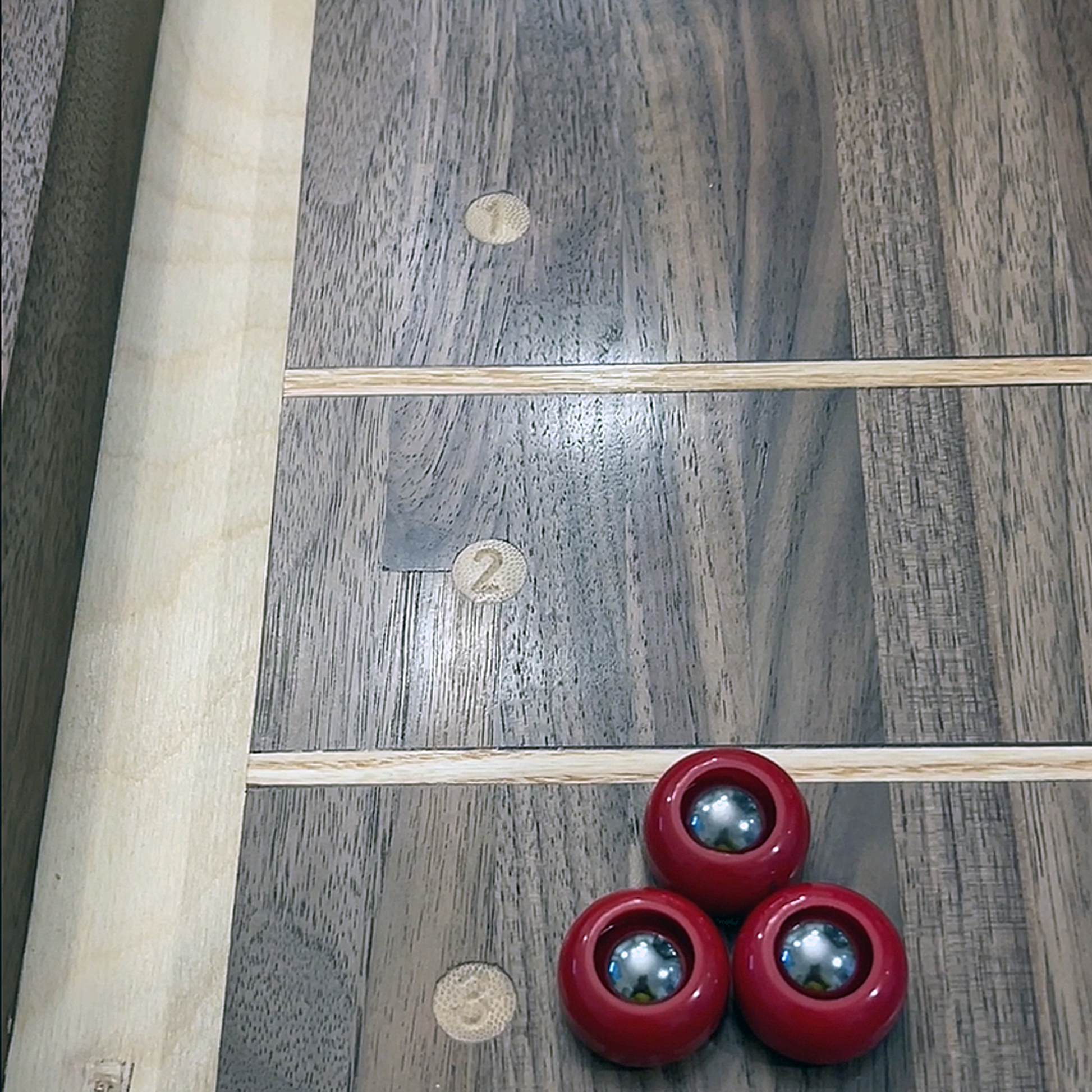 Three red pucks on a wooden lawn bowling green