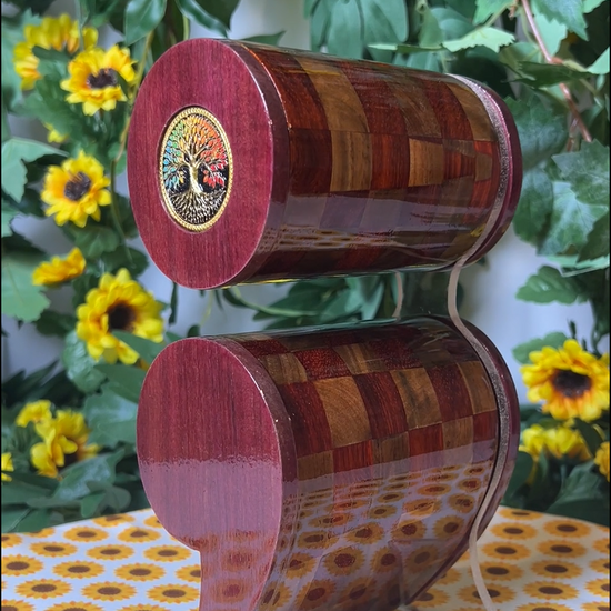 A video of a wooden semicolon shaped box with a checkered pattern on a floral tablecloth with sunflowers and greenery in the background.